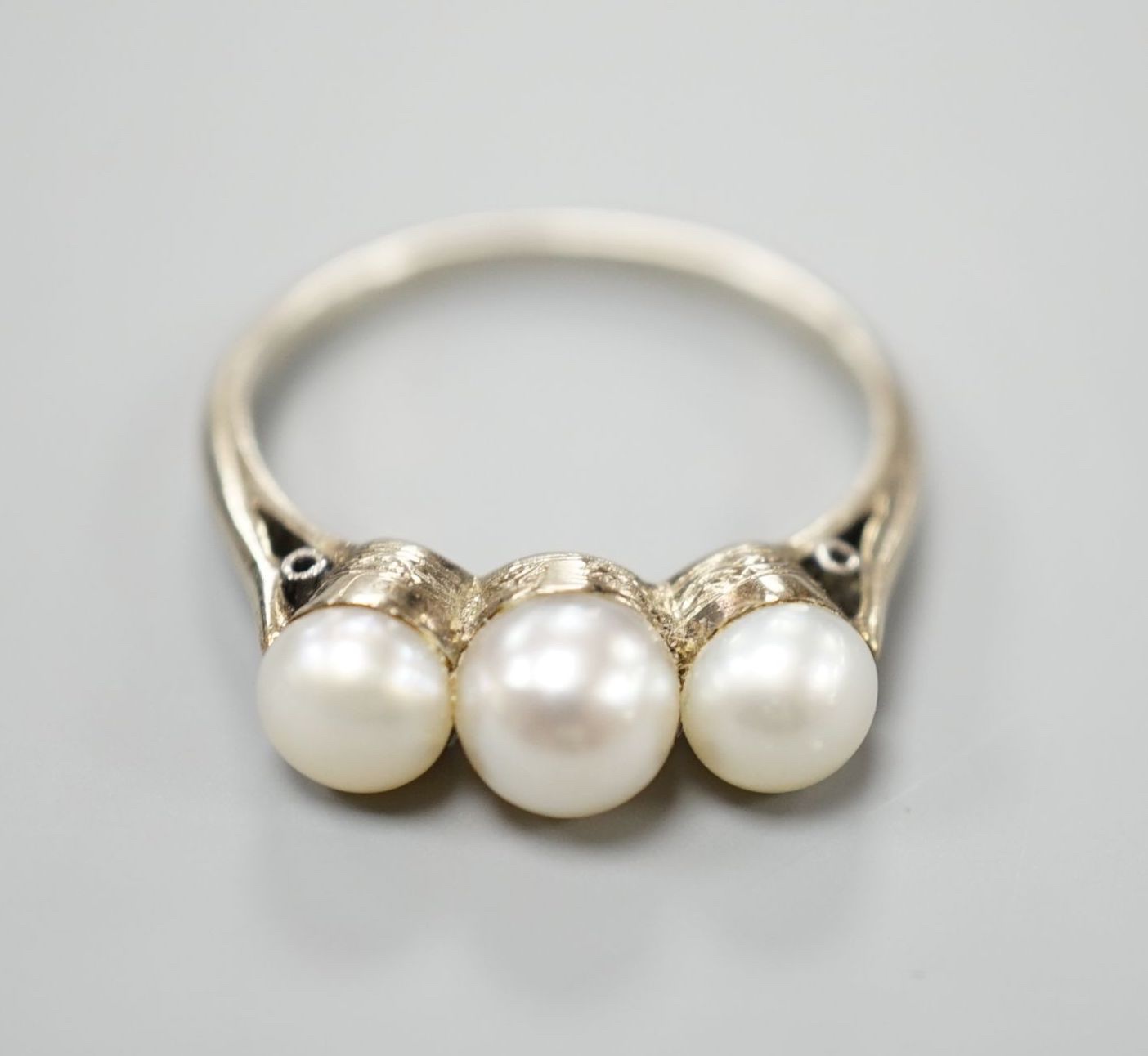 A white metal and three stone cultured pearl set ring, size M, gross weight 2.8 grams.